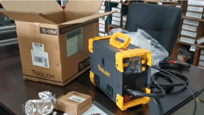 Tooliom TL-135M welder on a desk with its box and packaging materials.
