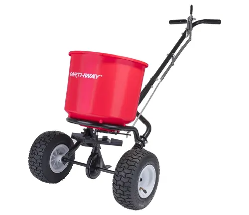 Red EarthWay broadcast spreader with large wheels and a handle, designed for spreading seeds, fertilizer, and other lawn products.