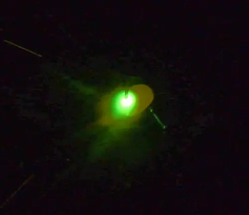 A close-up of a welding process using a HITBOX MIG200II MIG welder, showing a bright green welding arc in a dark setting.