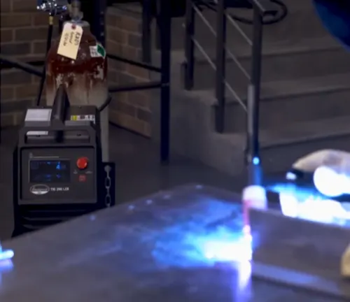 Eastwood Elite 200 Amp TIG Welder in use with a welding torch in action and a gas cylinder in the background.