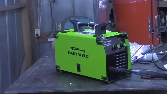 Forney Easy Weld 140 FC-I flux core welder positioned on a metal workbench in an industrial setting.