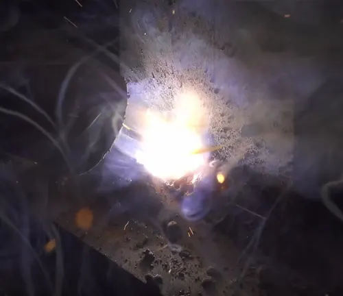 Intense welding arc and sparks from a flux-cored welder.