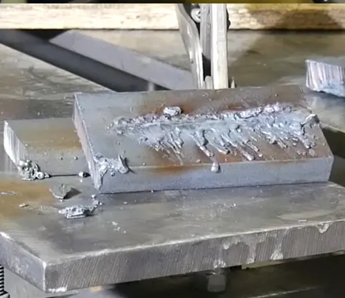 Metal slab with rough edges and molten residue on a cutting table, post-cut with Hypertherm Powermax45 XP.