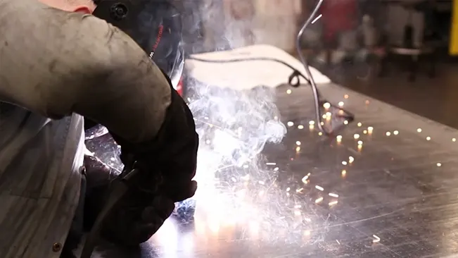 Person welding with sparks flying, using an Ironton 125 Flux-Cored Welder.