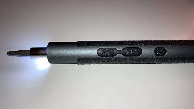 Electric pen screwdriver with LED light on white surface.