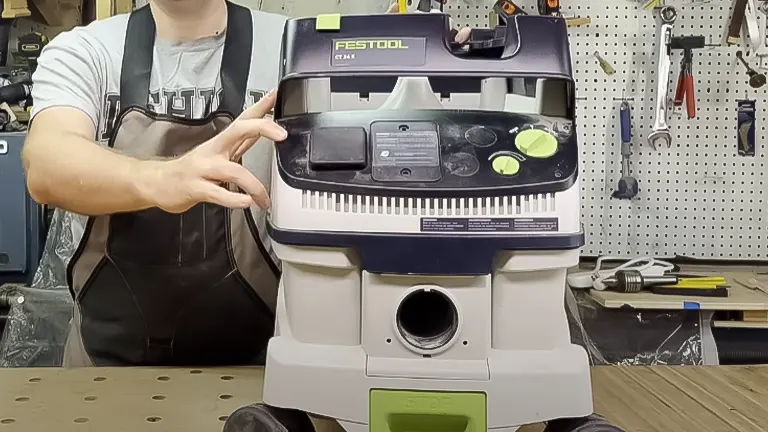 Person demonstrating a Festool dust extractor in a workshop