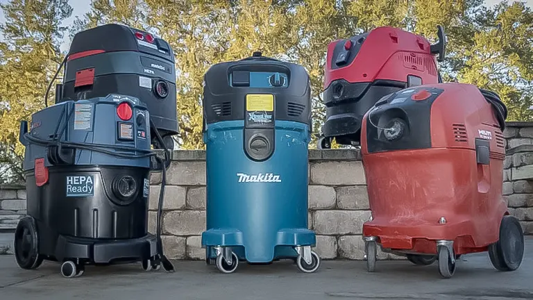 Four industrial dust collectors of different models and colors displayed outdoors