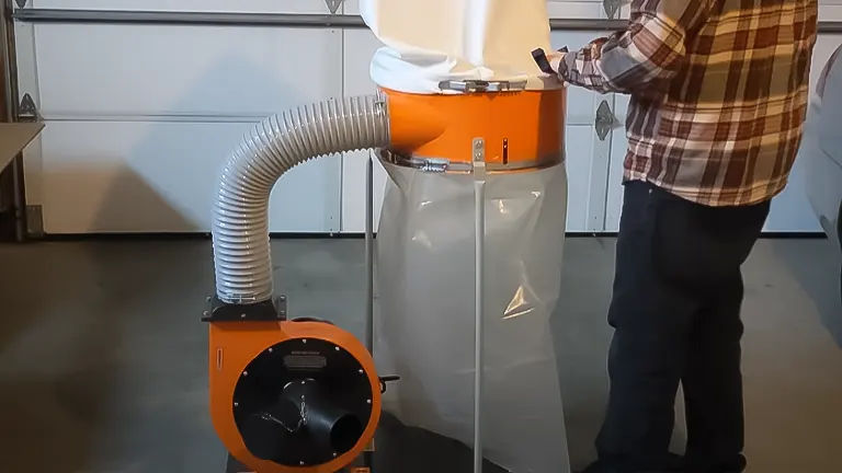 Person adjusting a WEN dust collector with an orange body and white filter in a garage
