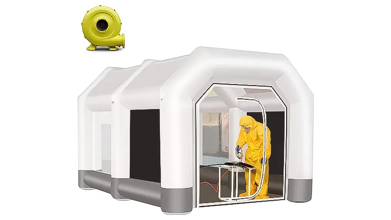 A white portable paint booth with a person in protective gear painting inside and a yellow blower to the side