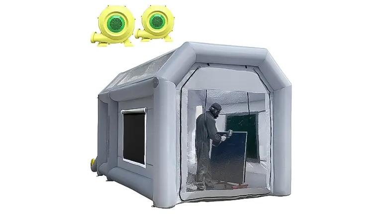 A gray inflatable paint booth with a clear front showing a person inside working, accompanied by two yellow blowers above