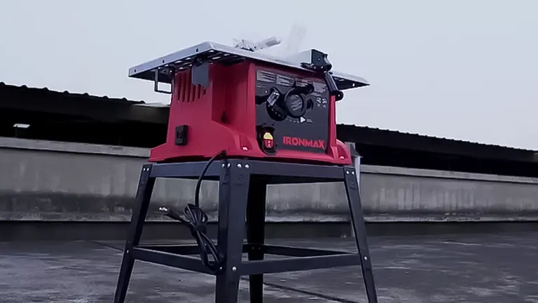 A red IRONMAX table saw with a safety guard on a black stand, positioned outdoors, suitable for expert woodworking
