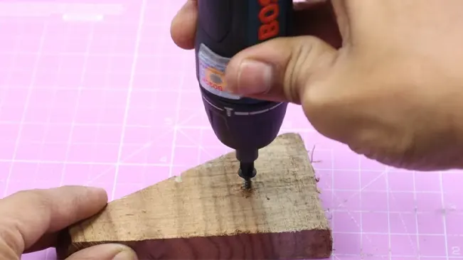 Bosch Go Smart Screwdriver in use on wood over pink grid.