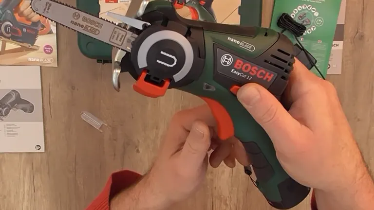 Person holding the Bosch Nano Mini Chainsaw with accessories below