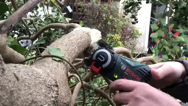 Person cutting big branch using Bosch Nano Mini Chainsaw