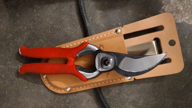 Corona BP 7100D Pruner with red handles in a tan leather sheath