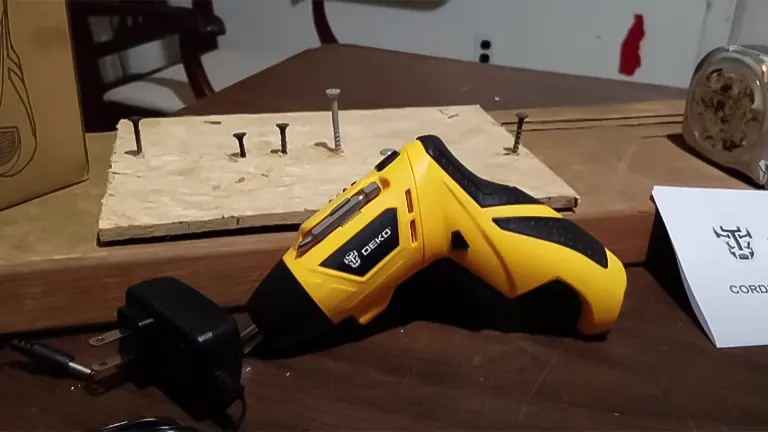 DEKOPRO 3.6V electric screwdriver on a workbench with screws and charger