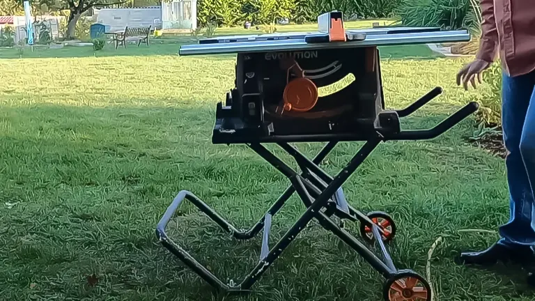 Outdoor setup of an Evolution Power Tools Rage 5-S Table Saw on a folding stand, with visible orange accents and a person standing beside it