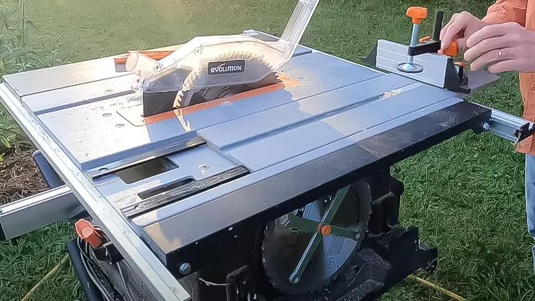 Close-up of a person adjusting an Evolution Rage 5-S Table Saw with an exposed cutting blade and orange safety features