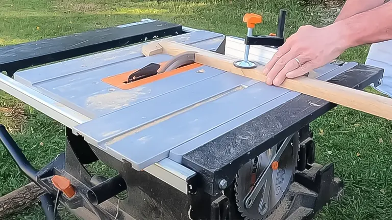 Person operating an Evolution Rage 5-S Table Saw, guiding a wooden beam across the blade for cutting