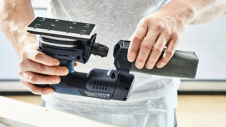 Person upside down the Festool RTSC 400 Orbital Sander and holding the chip collection bag