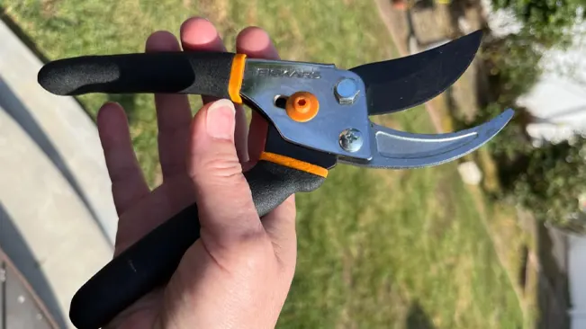Hand gripping Fiskars Pruners with open blades, outdoors