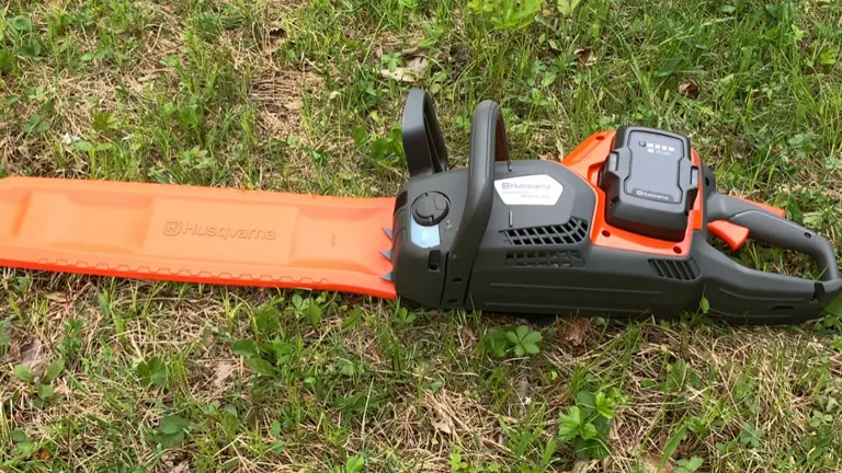 Husqvarna Power Axe 350i laying on the grass with bar and chain cover