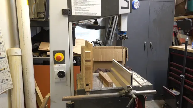 Bandsaw in a workshop with wood on the table and safety controls