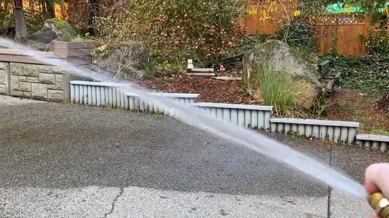 Person blocking the other side of the hose noozle to spray water further