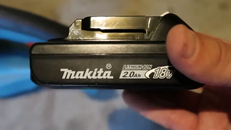 Person holding Makita 18V LXT Cordless Hedge Trimmer battery 