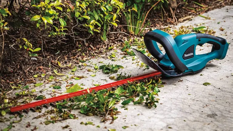 Makita 18V LXT Cordless Hedge Trimmer laying on the ground with cutted leaves