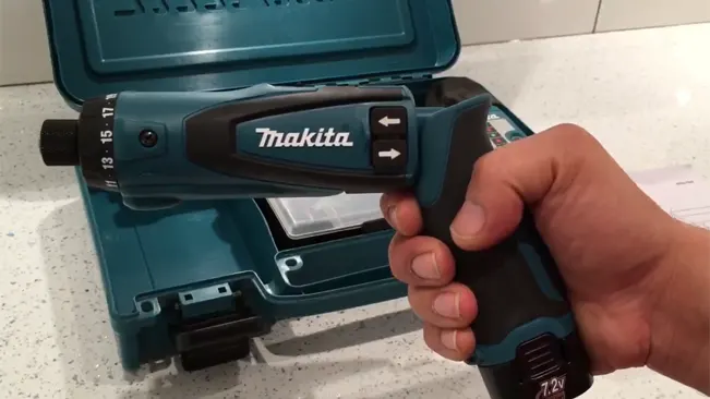 Hand holding a Makita 7.2V Driver-Drill with case in the background.