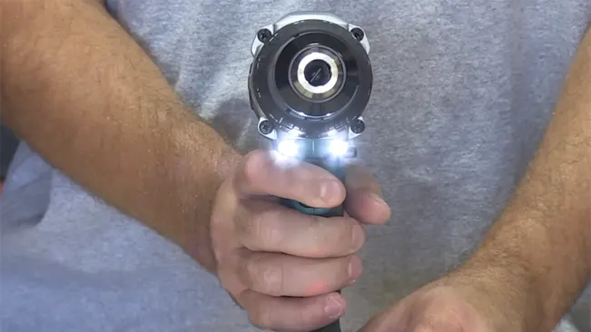Close-up of a person holding a drill with an illuminated LED work light.