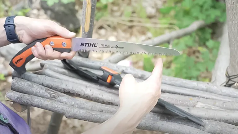 Close-up of a person's hands holding a Stihl PS 60 pruning saw, with the focus on the sharp teeth of the blade