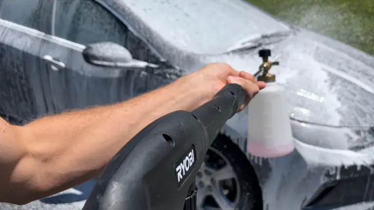 Person using the RYOBI 2000 PSI Pressure Washer wand cleaning the car