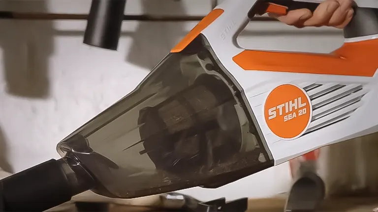 Close-up of the Stihl SEA 20 Cordless Handheld Vacuum Cleaner in use, highlighting its transparent dust container and orange branding
