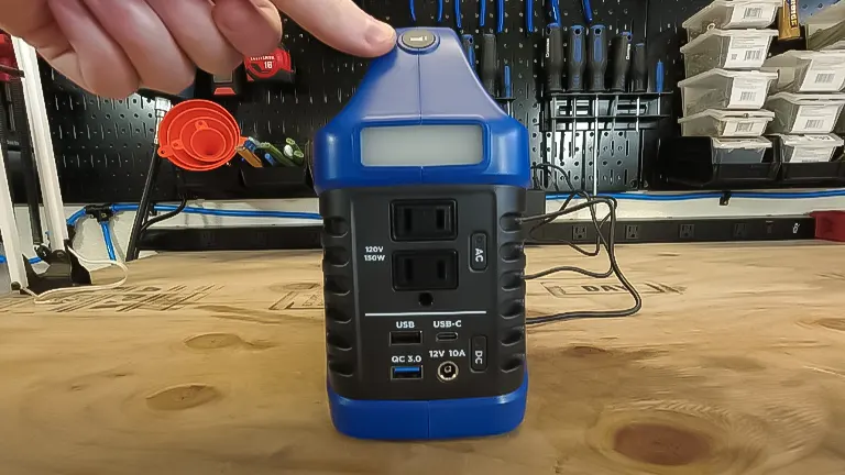 A Westinghouse iGen200s portable power station displayed on a workbench, with a person's finger pressing the power button