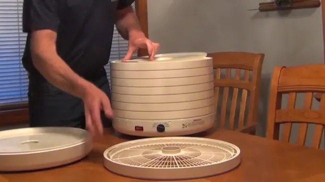 Person assembling a food dehydrator on a dining table
