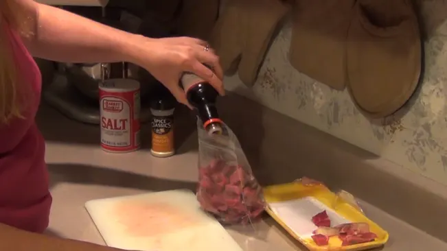 Person seasoning meat in a kitchen.