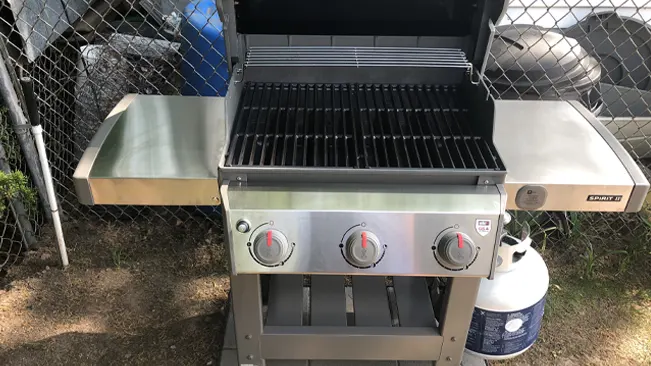 clean, open stainless steel barbecue grill with three control knobs and two side shelves