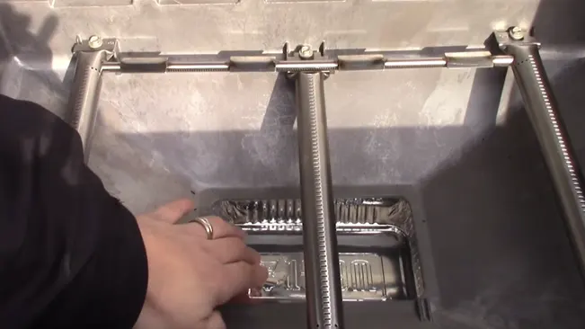 person’s hands adjusting a rectangular, metallic component inside a machine