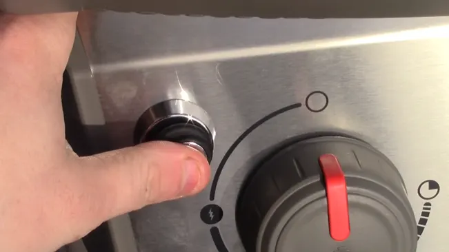 close-up of a person’s hand adjusting a knob on a stainless steel stove