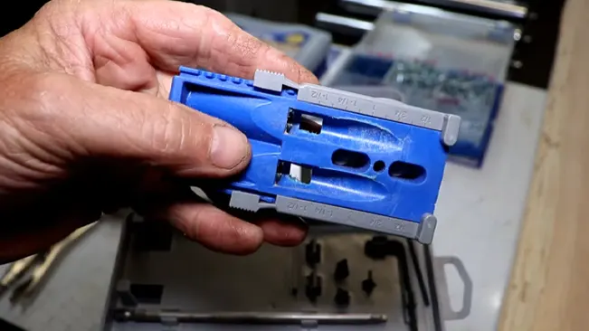 close-up of experienced hands holding a blue pocket hole jig in a well-organized workshop