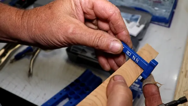 person measuring a wooden piece with a blue ruler in a workshop setting, indicating manual work