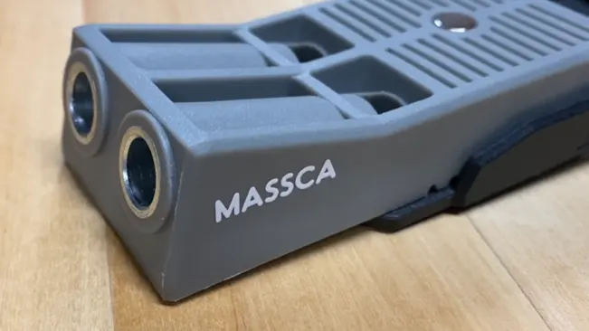 Close-up of a gray MASSCA pocket hole jig on a wooden surface.