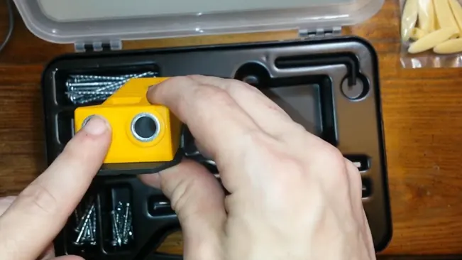 person examining a small, bright yellow tool with a circular hole in the middle