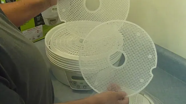 Person assembling a white food dehydrator