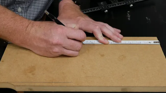 Person measuring and marking a piece of wood with a ruler and pen