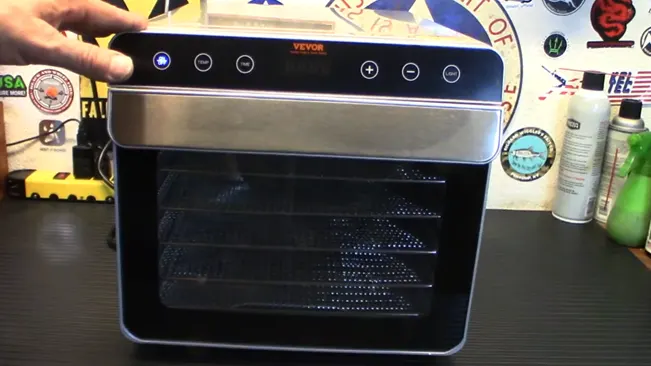 Person demonstrating a dehydrator with a digital interface on a countertop