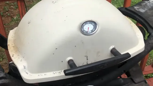 Close-up of a dirty outdoor grill with a temperature gauge