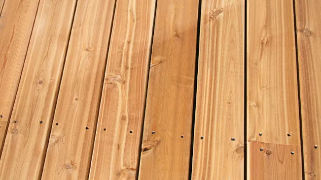 Close-up view of parallel wooden planks with visible grain patterns and embedded screws. Cedar